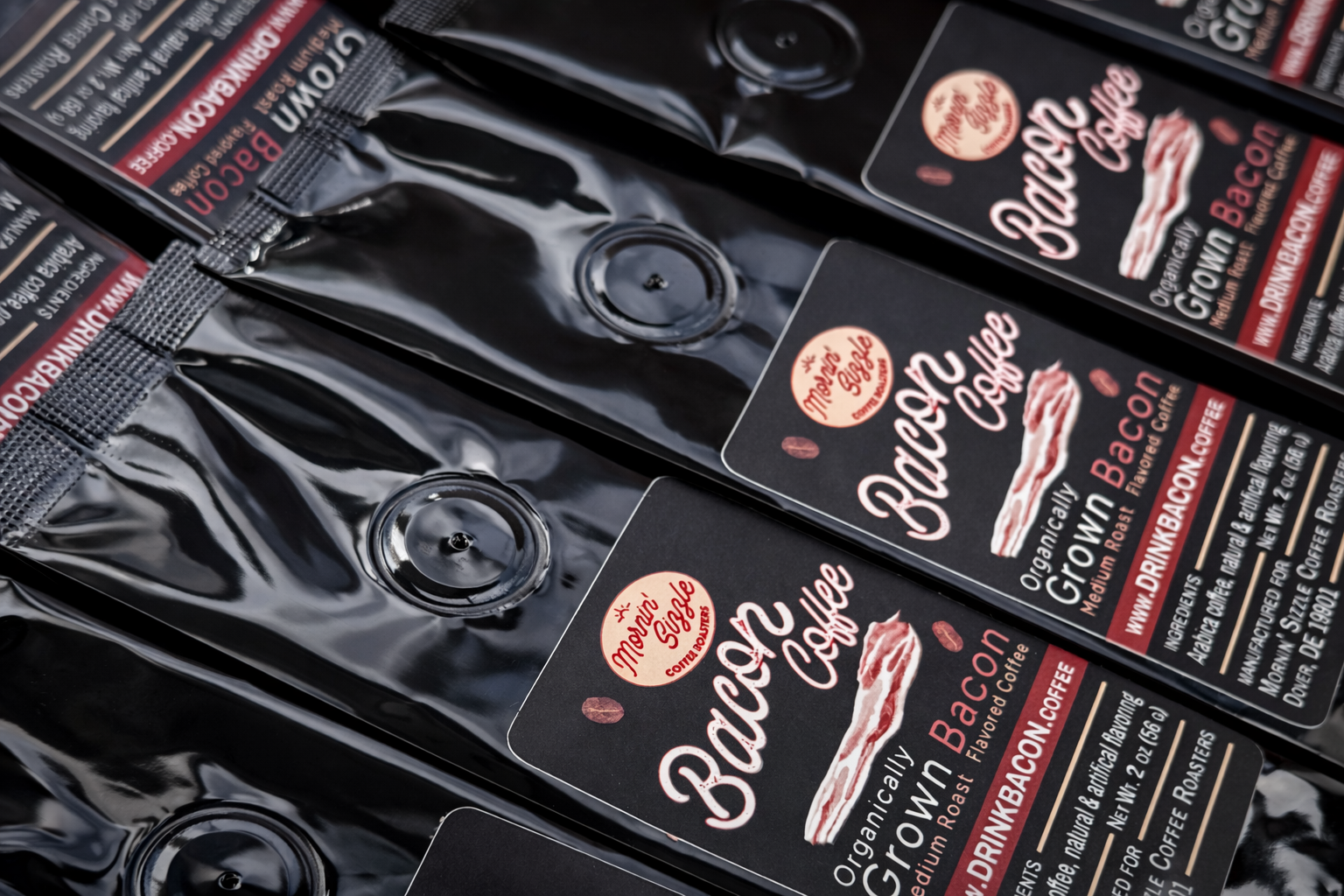 Close-up of black 2 oz Mornin' Sizzle Bacon Bitz coffee pouches